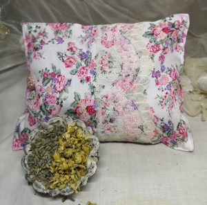 Floral pink herbal pillow with a dish of dried chamomile and lavender